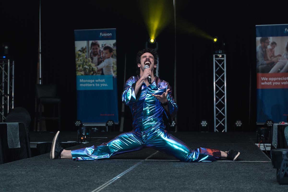 A performer on stage under lights at a sponsored corporate event