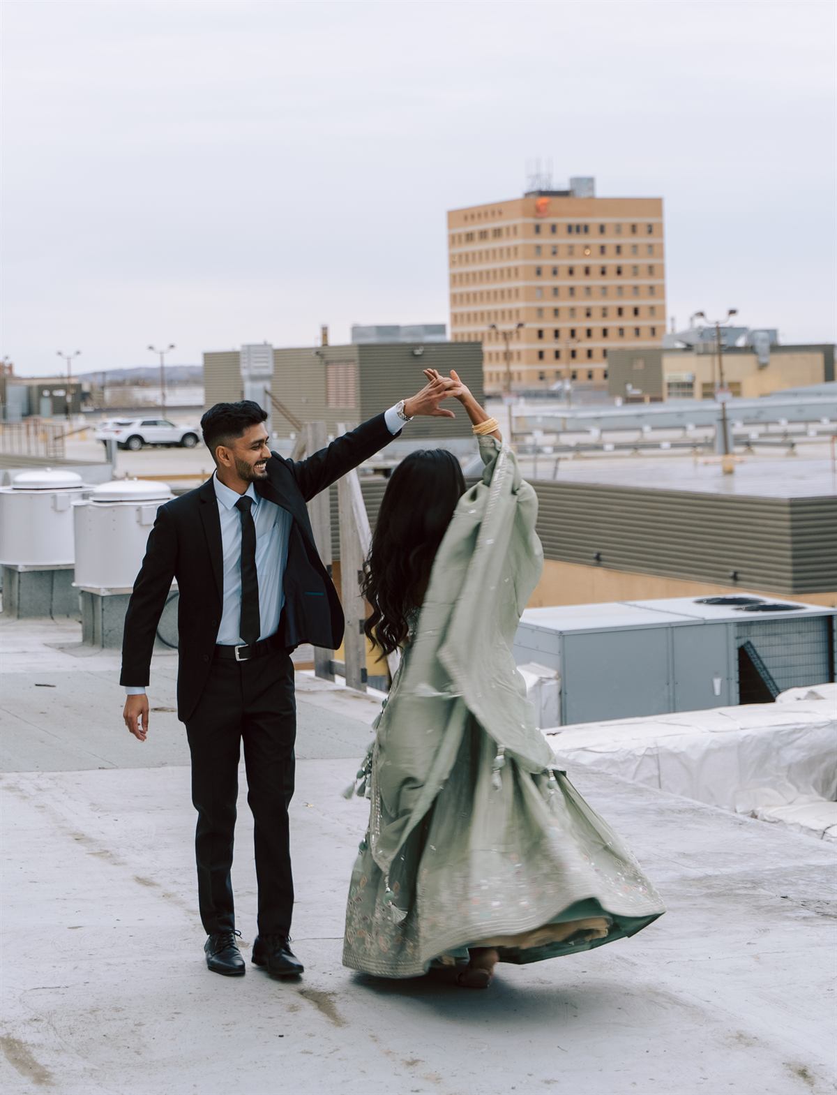 A couple dancing on a rooftop, caught mid-twirl for a vertical wedding reel
