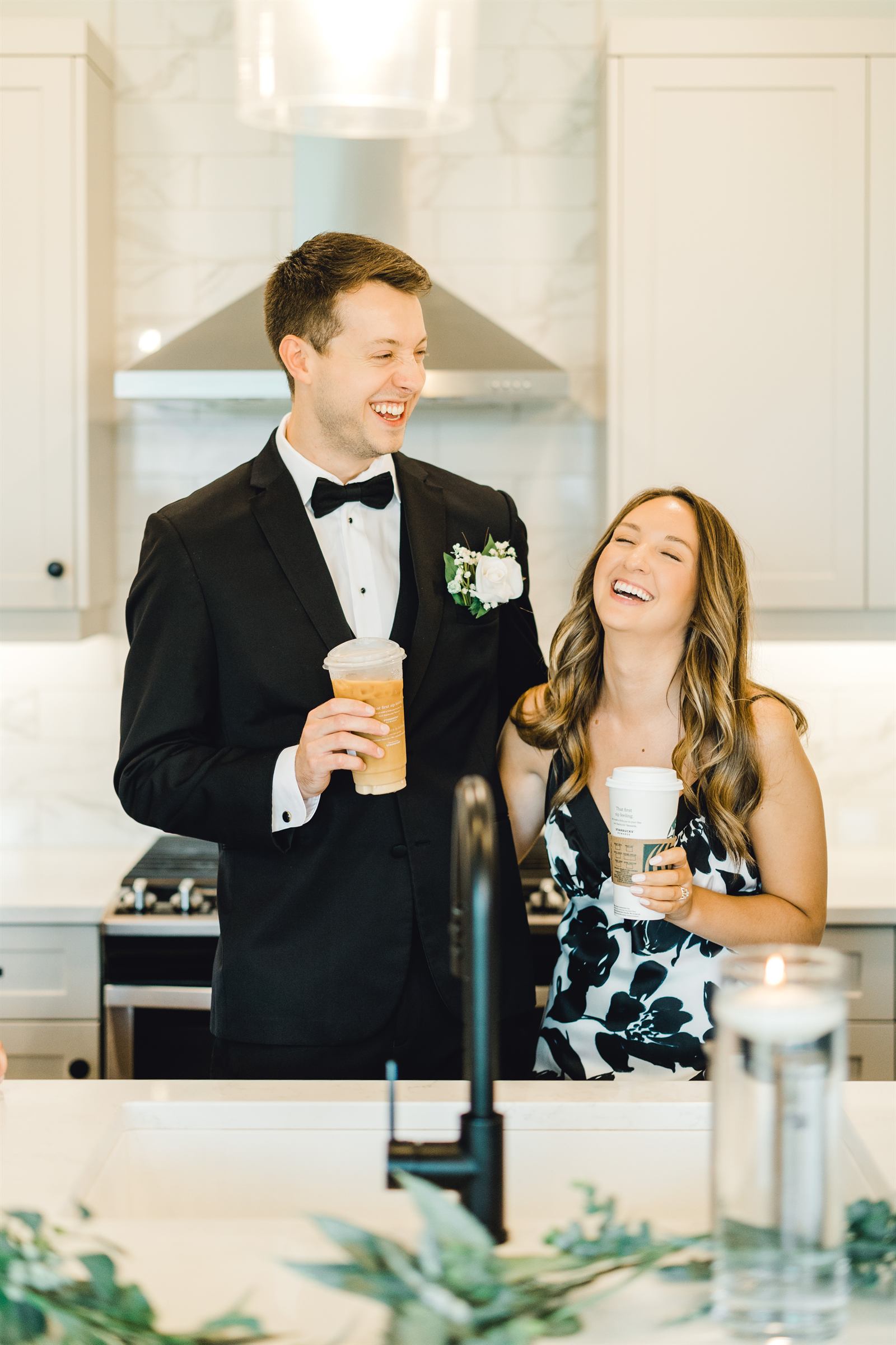 A couple laughing together with coffee while getting ready on their wedding morning